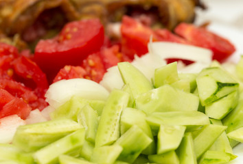 sliced tomatoes and cucumbers with greens on a plate