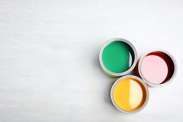 Cans with paint on light background, top view. Space for text