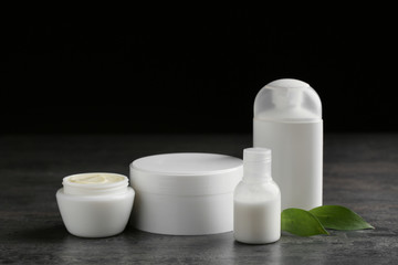 Jars with cream and bottles on dark table. Hand care cosmetics
