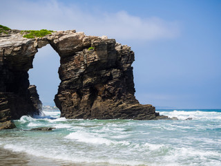 Fototapeta na wymiar Entorno natural de La Playa de Las Catedrales con arcos de piedra sobre la arena, en Lugo, Galicia, vacaciones en España, verano de 2018