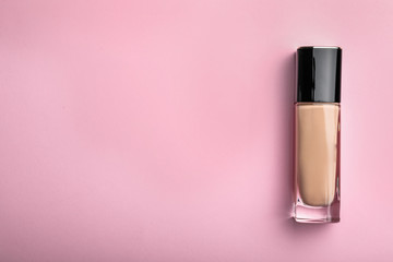 Bottle of skin foundation and space for text on color background, top view