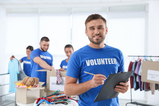 Male volunteer with clipboard listing donations indoors