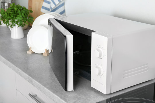 Open modern microwave oven on table in kitchen
