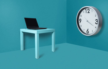 On the table lies an open laptop and a huge clock hanging on the wall in the office on a blue, pastel background. The concept of work, hours of work, waiting for the end of the task.