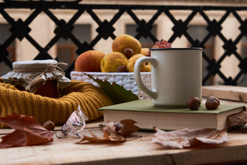 Cup of coffee old book glasses and autumn leaves with fruit basket on rustic wooden table on terrace background. Morning breakfast, seasonal, book reading, Sunday relaxing and still life concept