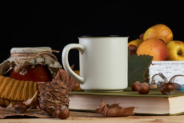 Autumn leaves, cup of coffee, warm scarf, fruits basket , jam jar, book with glasses on the table on black background, close-up. Morning breakfast seasonal book reading, Sunday relaxing concept