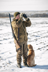 Охотник смотрит в бинокль с собакой