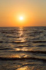 Bright sunset with large yellow sun under the sea surface. Sunset over sea landscape. Beautiful sunset with sky over calm sea in tropical island