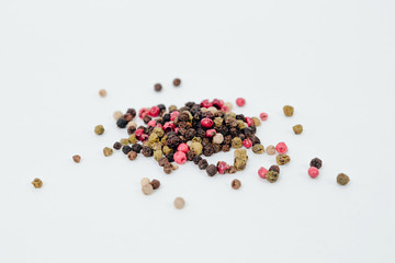 Colorful peppercorns isolated on white background. Colorful pepper strewn on a white background. The concept of using herbs and spices for dishes. Improving the taste. Spicy taste of dishes.