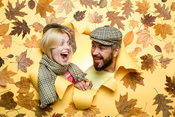 Happy couple, bearded man and blond woman in yellow background with leaves. Joyful couple is happy with the last warm days of autumn. Autumn couple wearing in autumn clothes and looks very sensually.