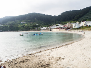 Fototapeta na wymiar Paisaje de playa de arena blanca con barcas de colores y agua verde y transparente, en Praia da Concha en Lugo, España, verano de 2018