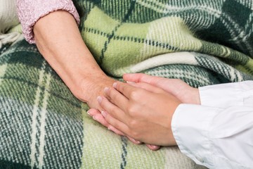 Young Woman's Hands Touching and Holding an Old Woman's Hand