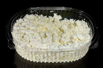 Low-fat cottage cheese in a one-time use plastic bowl with text space, isolated on a black background