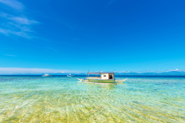 Crystal clean ocean with coral and a boat in Moalboal, Cebu, Philippines. Copy space for text.