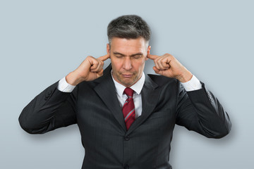 Businessman With Eyes Closed And Fingers In His Ears
