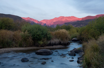 Alpine sunrise on mountains over creek and meadow