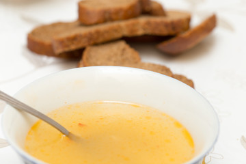 Soup with meatballs in a white bowl on the wooden background.