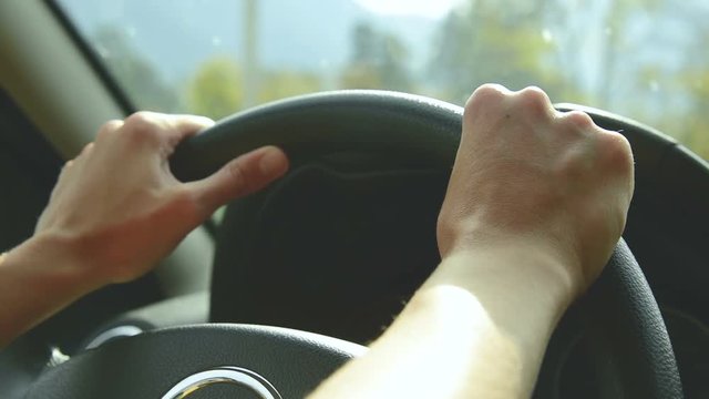 Close-up on open aperture. The girl drives a car on a country road. Women's hands on the steering wheel