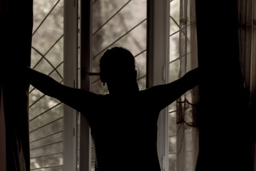 A young girl opens the curtains in the morning and relaxing. photo black and white