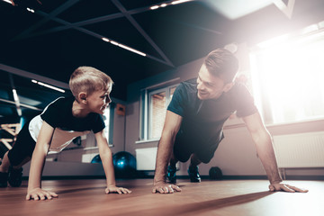 Father And Son Are Doing Push Ups In The Gym.