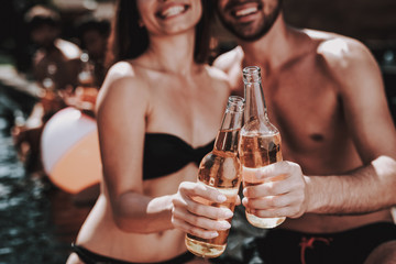 Smiling Couple with Alcoholic Drinks at Poolside
