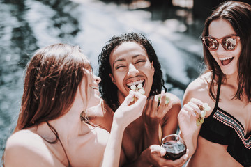 Young Smiling Women Drinking Wine at Poolside