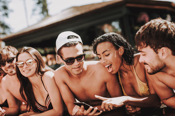 Young Smiling Friends using Smartphone at Poolside