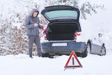 Man standing in front of damaged car holding bottle of antifreeze coolantin.