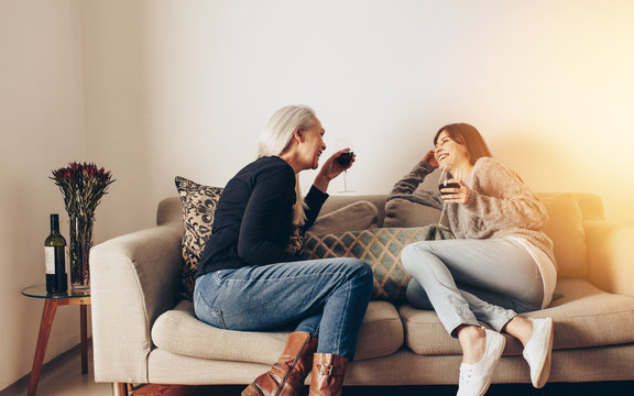 Two women sitting on couch at home talking