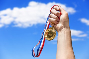 Fototapeta na wymiar Gold medal with ribbon in hand on