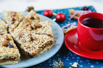 Fruitcake, decor, branches of spruce, plate with a cake and red cup of coffee or tea on the blue placemat. New year and Christmas decoration concept.  copy space