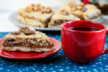 Fruitcake, decor, branches of spruce, plate with a cake and red cup of coffee or tea on the blue placemat. New year and Christmas decoration concept.  copy space