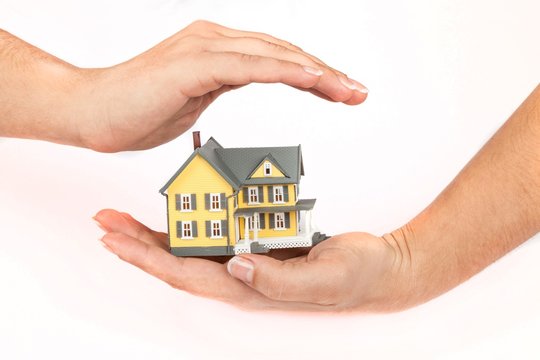 Women's Hands Holding and Protecting a Model of a House