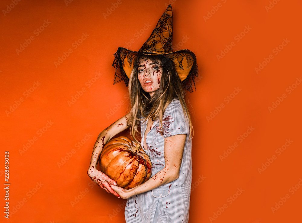 Wall mural model with bloody hands and blood on face. happy young woman halloween costume with hat standing ove - Wall murals
