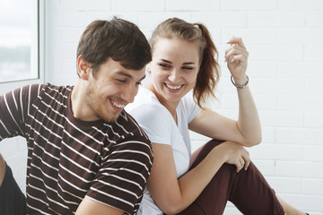 Happy girl and guy, cute couple looking out the window in their new home