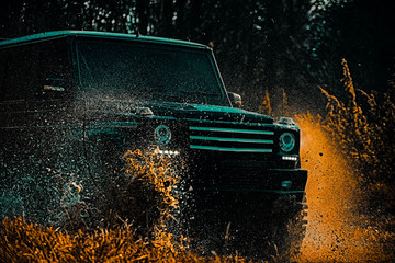 Jeep crashed into a puddle and picked up a spray of dirt. Off-road travel on mountain road. Road adventure. Adventure travel. © Volodymyr
