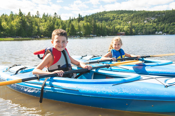 Summer vacation Portrait of cute boy and girl kayaking the on river