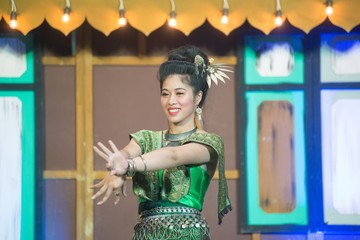 The lady in Middle thai classical dancing suit is showing pattern of traditional dancing on platform.