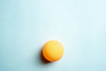 Orange ping pong ball on blue background