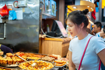 Girl trying Hong Kong local street food - curry fish balls