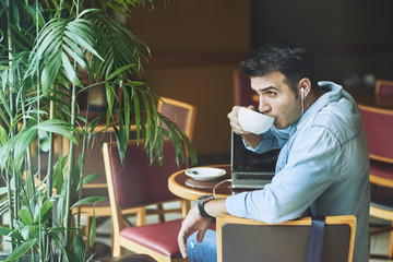 Attractive young man enjoying cup of cappuccino in coffeeshop
