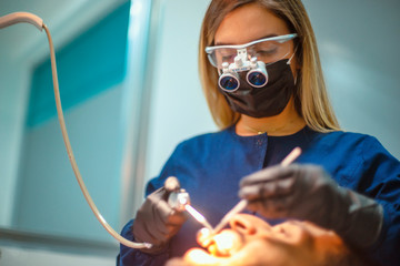 close-up young woman dentist working with magnifying glasses