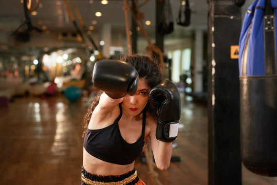 Serious young Asian woman boxing in gym