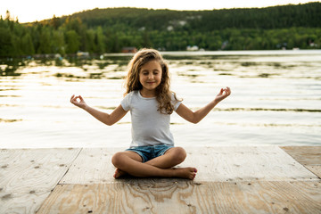 Fototapeta na wymiar child girl Yoga relax in pier at the sunset
