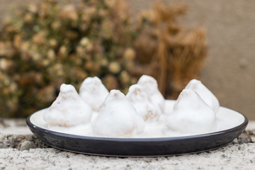 Vegan sweet truffle candies with white  coconut creamy frosting or icing on plate. Healthy dieting dessert