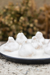 Vegan sweet truffle candies with white  coconut creamy frosting or icing on plate. Healthy dieting dessert