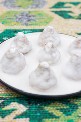 Vegan sweet truffle candies with white  coconut creamy frosting or icing on plate. Healthy dieting dessert
