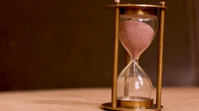 Female hand flipping an hourglass on white background with reflection and copy space on the right