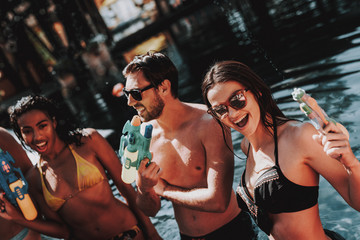 Young Smiling People in Pool with Water guns