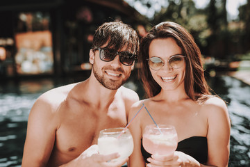 Smiling Couple Drinking Cocktails at Poolside